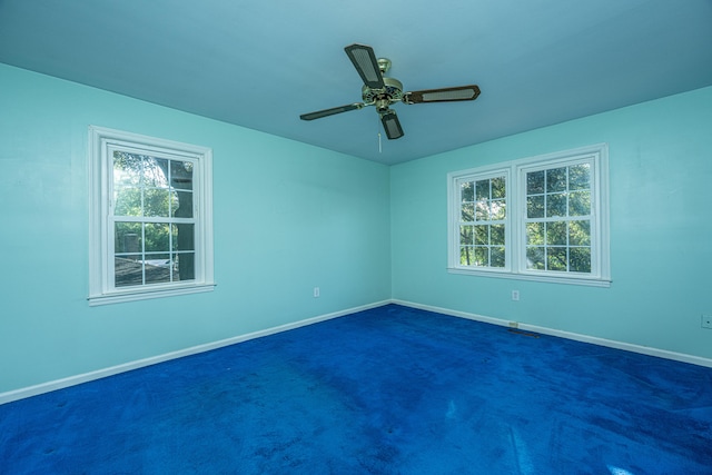 carpeted spare room featuring ceiling fan and plenty of natural light