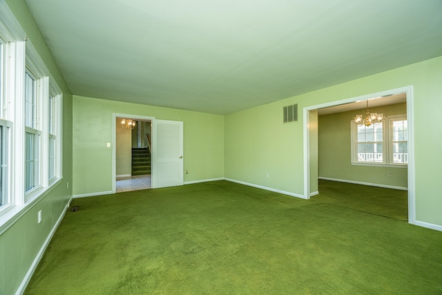 unfurnished room with carpet flooring and a chandelier