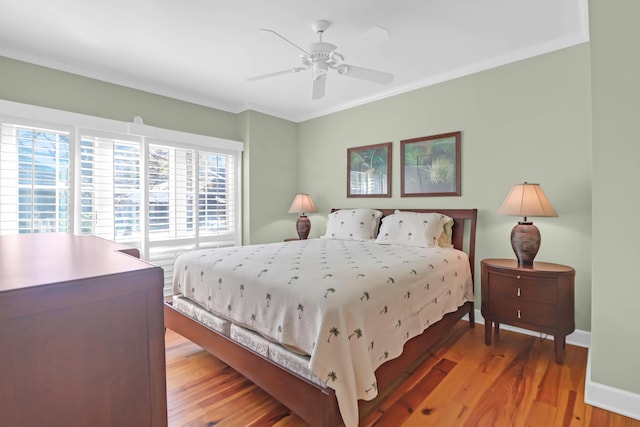 bedroom with crown molding, light wood-style flooring, a ceiling fan, and baseboards