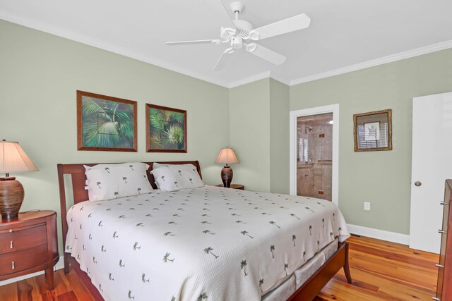 bedroom with crown molding, wood finished floors, baseboards, and ensuite bathroom