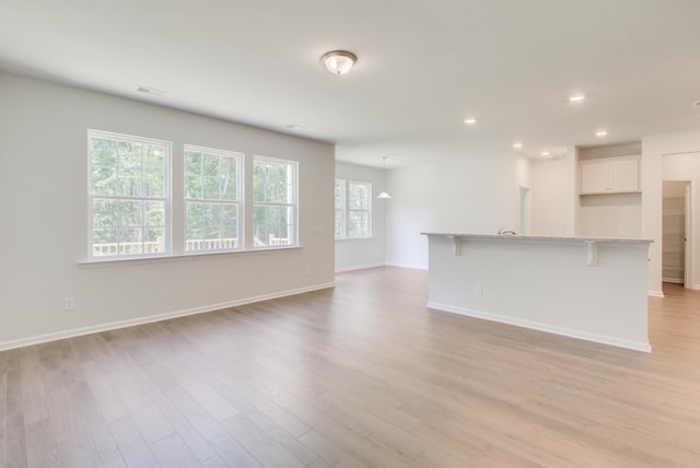 unfurnished living room with recessed lighting, visible vents, light wood-style flooring, and baseboards