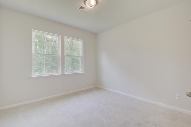 unfurnished room with carpet, visible vents, and baseboards