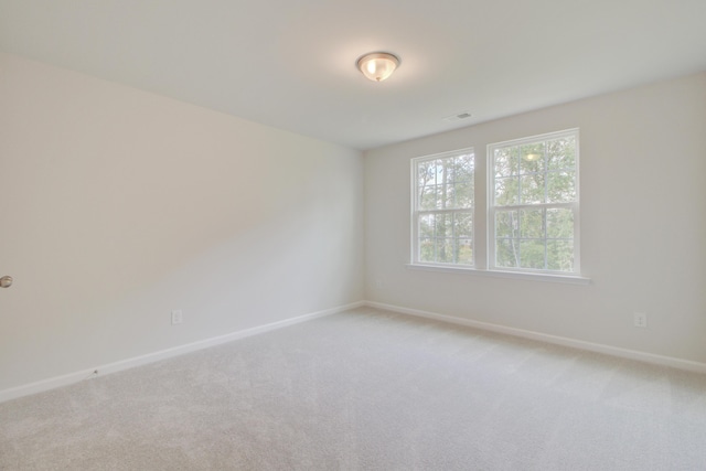 unfurnished room featuring light carpet, visible vents, and baseboards