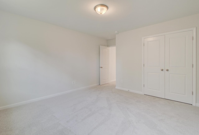 unfurnished bedroom featuring baseboards, a closet, and light colored carpet