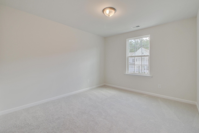 spare room with light carpet, visible vents, and baseboards