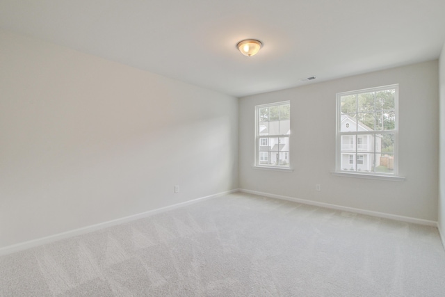 spare room featuring light carpet, visible vents, and baseboards