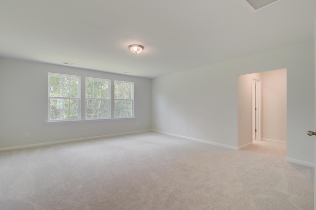 spare room featuring baseboards, visible vents, and light colored carpet