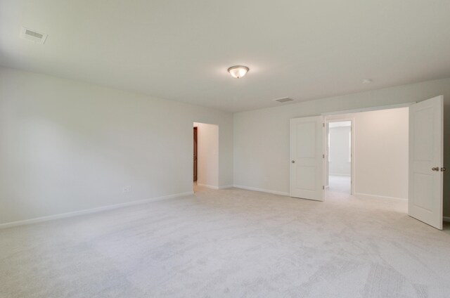 unfurnished room featuring visible vents, light carpet, and baseboards