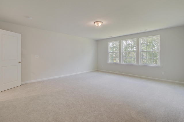 empty room with light carpet, visible vents, and baseboards