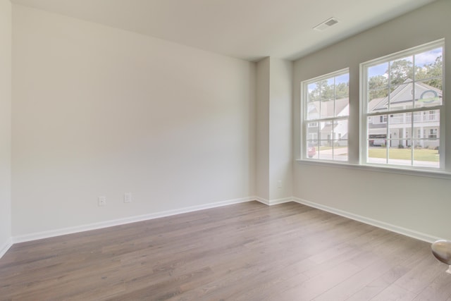 empty room with baseboards, visible vents, and wood finished floors