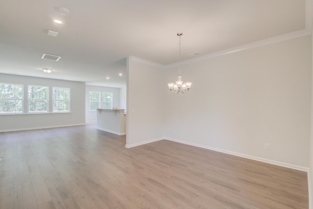 spare room featuring a chandelier, wood finished floors, visible vents, and baseboards