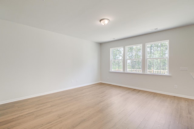 spare room featuring baseboards, visible vents, and light wood-style floors