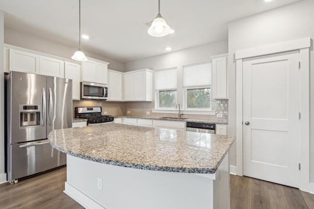 kitchen featuring decorative light fixtures, a kitchen island, dark hardwood / wood-style flooring, white cabinetry, and stainless steel appliances