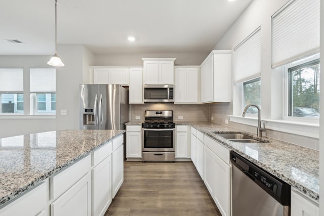 kitchen with white cabinetry, sink, stainless steel appliances, and decorative light fixtures