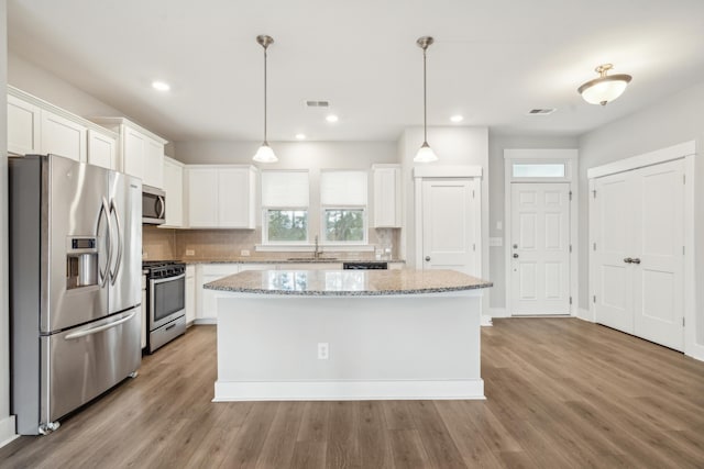 kitchen with a kitchen island, white cabinets, light hardwood / wood-style flooring, and appliances with stainless steel finishes