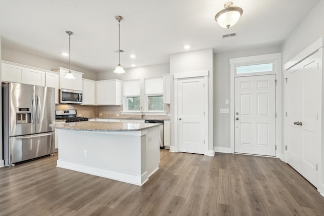 kitchen featuring a center island, hanging light fixtures, hardwood / wood-style flooring, white cabinetry, and stainless steel appliances