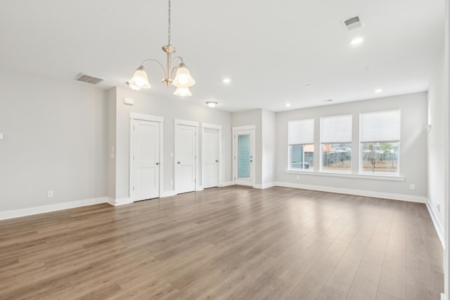 unfurnished living room with hardwood / wood-style floors and a notable chandelier