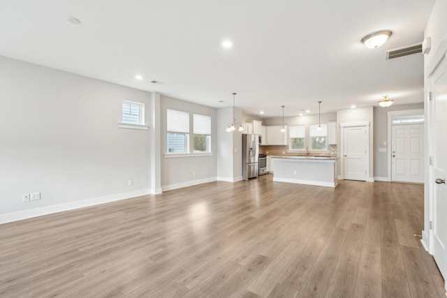 unfurnished living room with a chandelier and light hardwood / wood-style floors