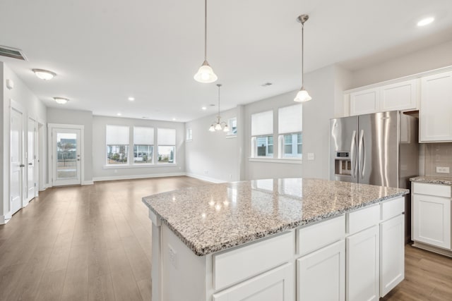 kitchen with a center island, white cabinets, stainless steel refrigerator with ice dispenser, decorative light fixtures, and light hardwood / wood-style floors