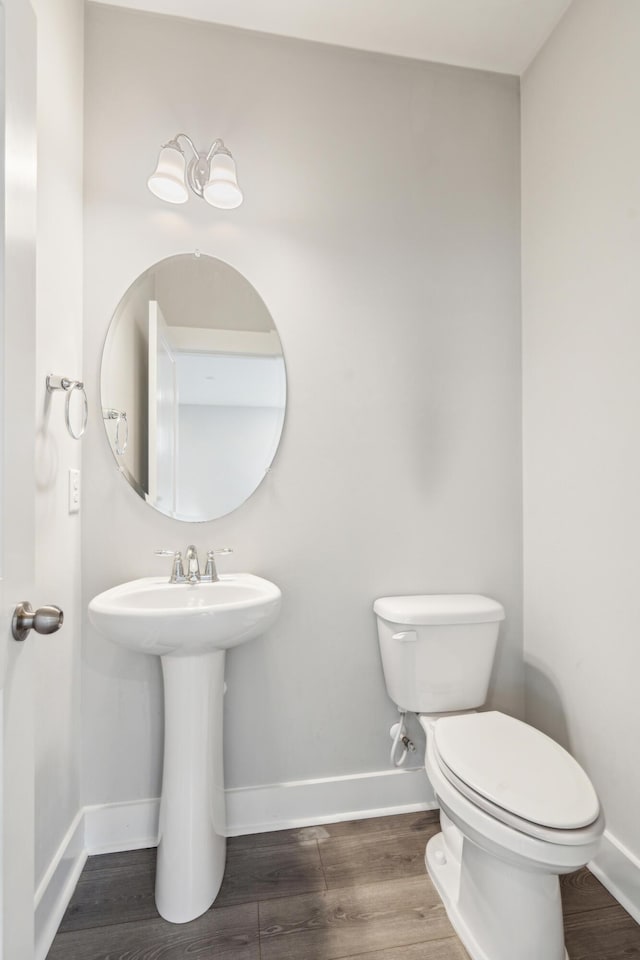 bathroom with toilet, wood-type flooring, and sink