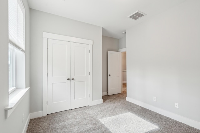 unfurnished bedroom featuring light carpet and a closet