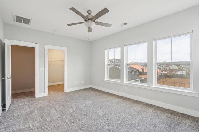 unfurnished bedroom with carpet, ceiling fan, a walk in closet, and a closet