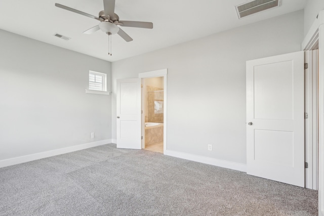 unfurnished bedroom featuring ceiling fan, light colored carpet, and ensuite bath