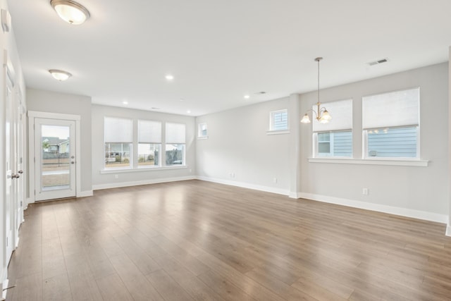 unfurnished living room with hardwood / wood-style floors and a notable chandelier