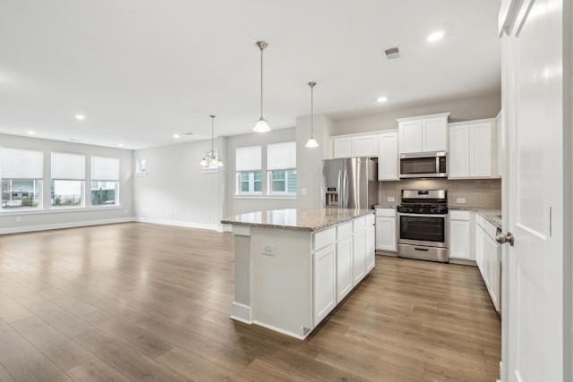 kitchen with pendant lighting, a healthy amount of sunlight, white cabinetry, and stainless steel appliances