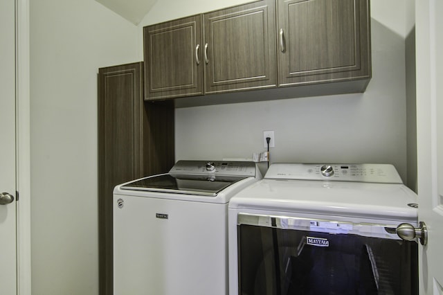 clothes washing area featuring cabinets and washing machine and clothes dryer