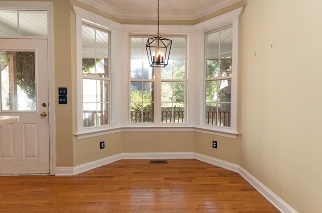 unfurnished dining area featuring light hardwood / wood-style flooring, ornamental molding, and a chandelier