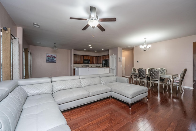 living room with ceiling fan with notable chandelier and dark hardwood / wood-style floors