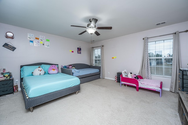 carpeted bedroom featuring multiple windows and ceiling fan