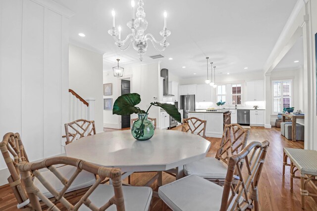 dining space featuring a chandelier, light hardwood / wood-style floors, and ornamental molding