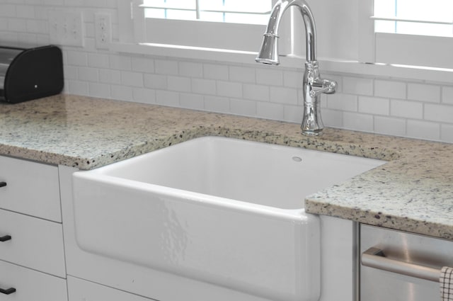 interior details with decorative backsplash, light stone countertops, and sink