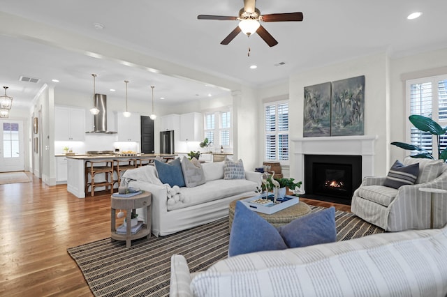 living room with ceiling fan, light hardwood / wood-style flooring, and crown molding