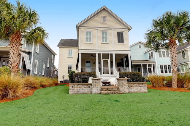 rear view of property with covered porch, ceiling fan, and a lawn