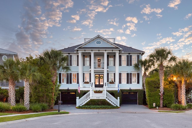 greek revival inspired property with an attached garage, stairway, covered porch, a balcony, and french doors