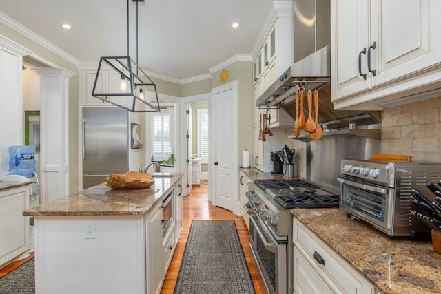 kitchen featuring built in appliances, light wood-style floors, crown molding, light stone counters, and white cabinetry