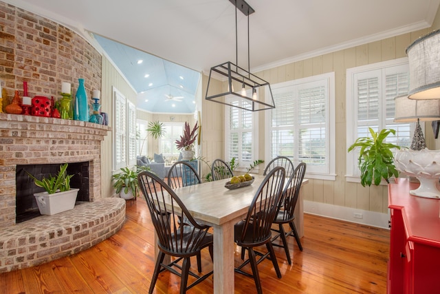 dining space featuring crown molding, hardwood / wood-style floors, plenty of natural light, a fireplace, and wooden walls