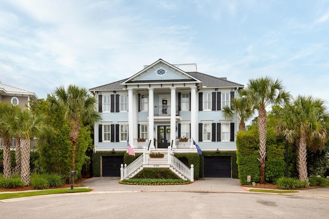 greek revival inspired property featuring a balcony, stairway, a porch, concrete driveway, and french doors
