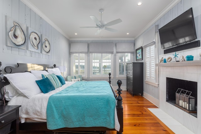 bedroom with crown molding, wood finished floors, a fireplace, recessed lighting, and a ceiling fan