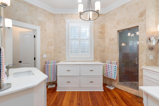 bathroom with crown molding, a sink, a stall shower, wood finished floors, and a chandelier