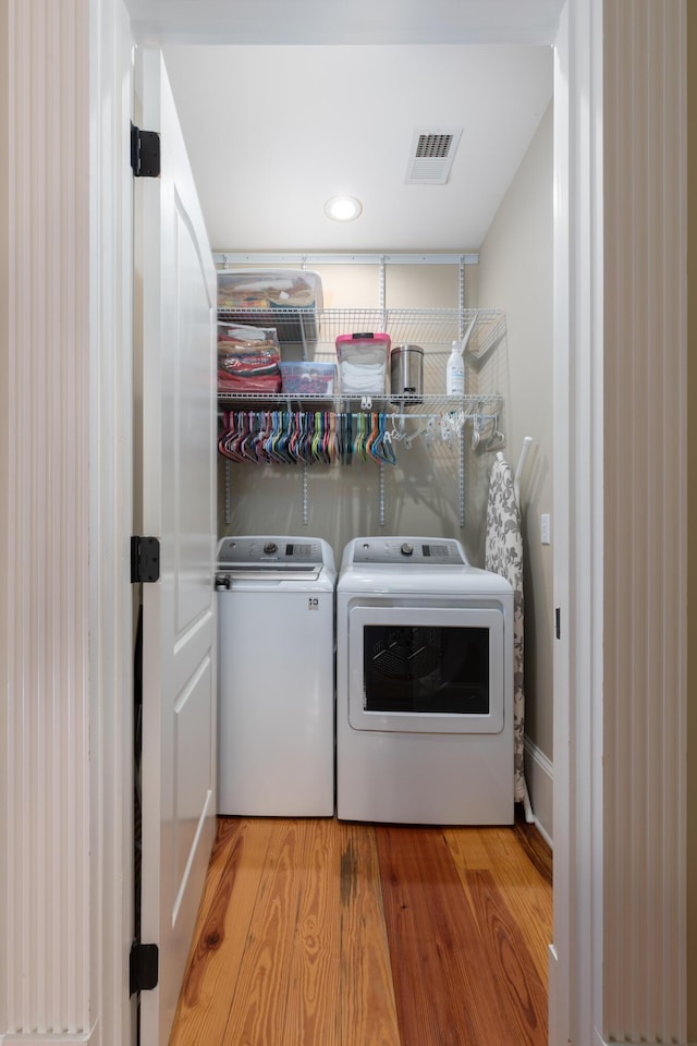 clothes washing area featuring separate washer and dryer and wood finished floors