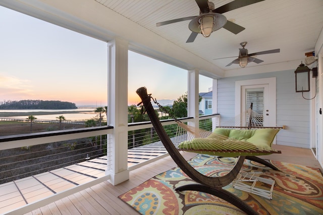 sunroom / solarium with a ceiling fan and a water view