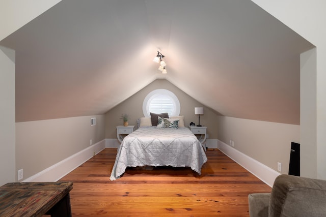 bedroom featuring baseboards, lofted ceiling, and wood finished floors