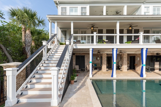 rear view of house featuring a ceiling fan, stairs, a balcony, a patio, and an outdoor pool