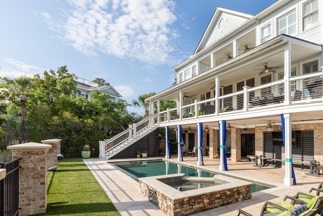 rear view of property with ceiling fan, a balcony, stairs, a patio area, and a pool with connected hot tub