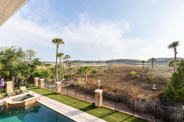 view of swimming pool featuring fence and a pool with connected hot tub