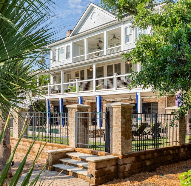 view of front of home featuring a balcony, a ceiling fan, and a fenced front yard